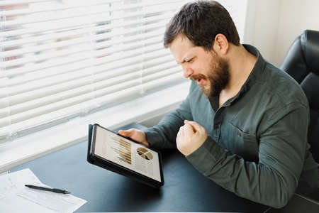 Male successful broker working with graphs and diagrams on tablet.の写真素材