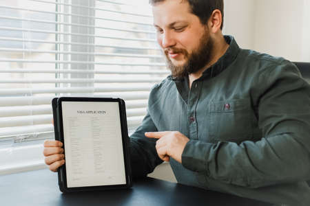 Close up businessman reading visa application on tablet.の写真素材
