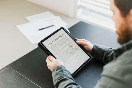 Man reading elecronic rental agreement on tablet.の写真素材