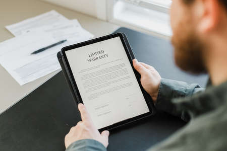 Close up man reading limited warranty tamplate on tablet.の写真素材