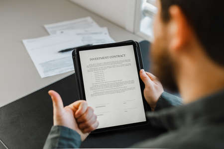Man reading template investment contract on tablet.の写真素材