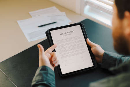Close up man reading house rental contract on tablet.の写真素材