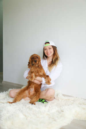 Young woman sitting on floor and playing with spaniel dog.の写真素材