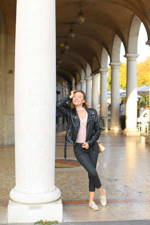 Young woman leaning on column, building archs in background.の写真素材
