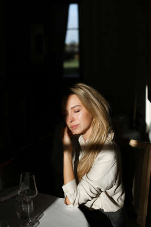 Young woman sitting at cafe with wineglass in black background.の写真素材