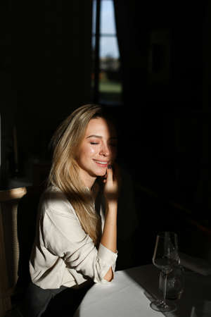 Caucasian woman sitting at cafe with wineglass in black background.の写真素材
