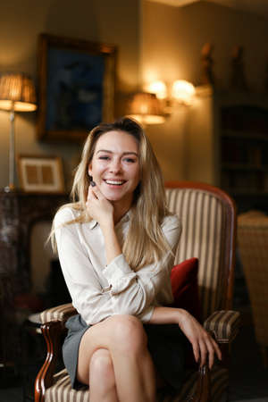 Portrait of smiling girl sitting in arm chair at home.の写真素材