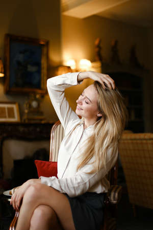 Portrait of blonde girl sitting in arm chair at home.の写真素材