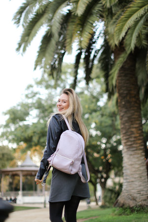 Young woman going near palm trees with backpack.の写真素材