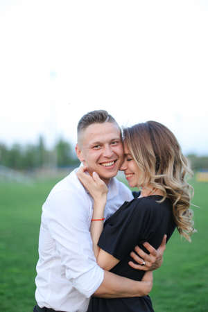 Young smiling man hugging woman on football field.の写真素材