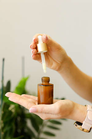 Natural skincare cosmetic hold in woman hands, creams and oils on bath background. Plant-based beauty products.の写真素材