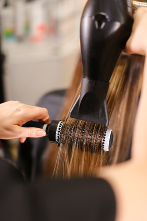 Stylist doing hairstyle beautiful brunetteの写真素材