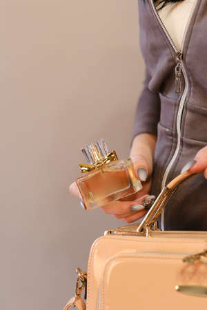 elegant sensual young woman holding perfume, golden tonesの写真素材