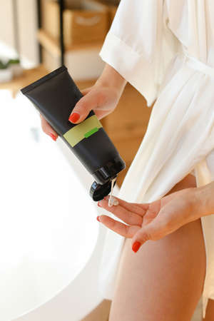 Beautiful fresh legs of young woman applying cream on it - indoorsの写真素材