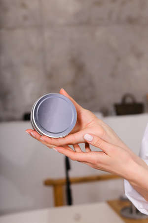 Woman holding botle or jar for spa cosmetics purpose in bathroom. Beauty blogger, salon therapy, minimalism concept, copyspaceの写真素材