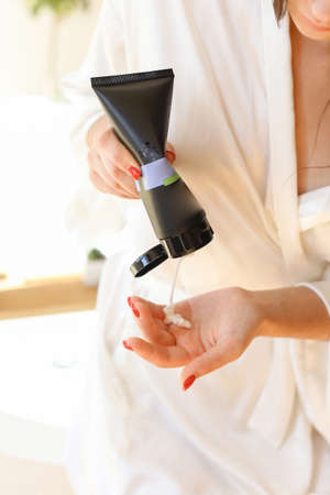 Woman holding botle or jar for spa cosmetics purpose in bathroom. Beauty blogger, salon therapy, minimalism concept, copyspaceの写真素材