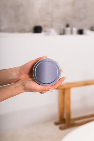 Woman holding botle or jar for spa cosmetics purpose in bathroom. Beauty blogger, salon therapy, minimalism concept, copyspaceの写真素材