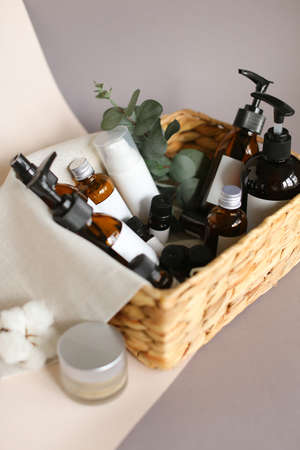 collection of various beauty hygiene tubes, bottles and jars in basket on gray backgroundの写真素材