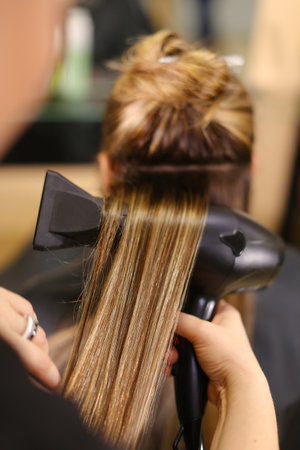 Stylist doing hairstyle beautiful brunetteの写真素材