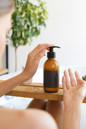 Womans holding botles with spa cosmetics in bathroom. Beauty blogger, salon therapy, minimalism concept, copyspaceの写真素材