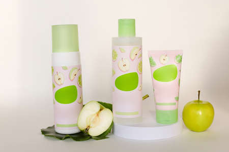 Green and white plastic cosmetics paste cream or gel tube and bottles, isolated on white background with appleの写真素材