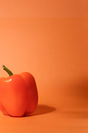 Fresh sweet orange pepper isolated on neutral orange background closeupの写真素材