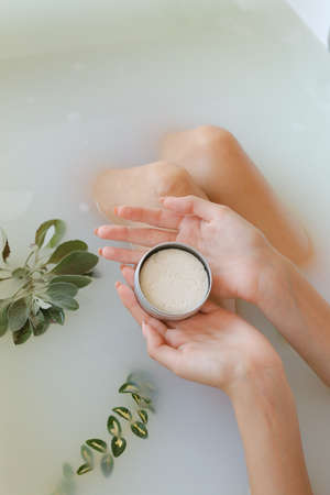 Top view of woman hands with solid soap on white water background, taking bathの写真素材