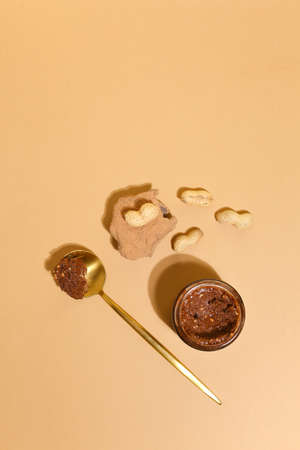 Natural cosmetics for skin care. Body scrub with peanut. beige background top view copy space
