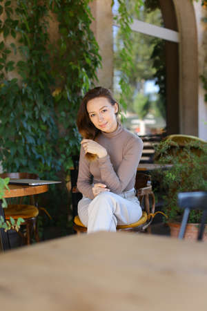 Young caucaisian woman posing at street cafe, closed laptop computer on table.の写真素材