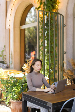 Young intelligent woman using laptop computer at street cafe outside.の写真素材