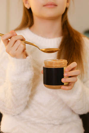 A young girl eat peanut butter on Holiday Christmas backgroundの写真素材