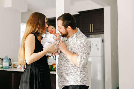 Portrait of young parents holding little female baby in flat.の写真素材