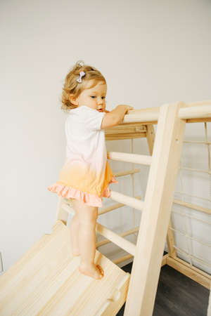 Baby girl play with developmental wooden structure at home or kindergarten or daycare centerの写真素材