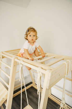 Baby girl play with developmental wooden structure at home or kindergarten or daycare centerの写真素材