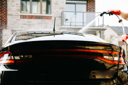 Close up black car washed by water jet, drops in background.の写真素材