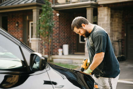 Man polishing car by polisher in front of house.の写真素材