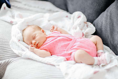 Newborn baby girl sleep on white blanket and wearing pink clothes.の写真素材