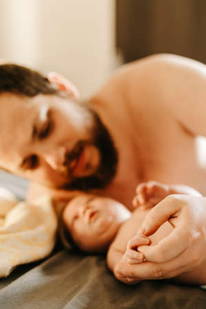 Close up focus on arms, portrait of man holding newborn baby.の写真素材