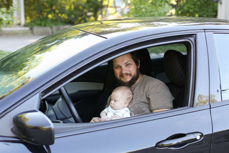 Caucasian father playing with litte baby in drivers seat in car.