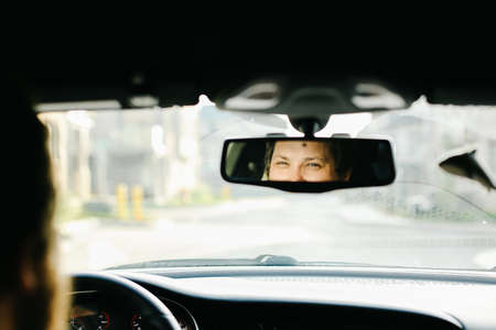 Smiling caucasian male driver reflected in mirror of car.