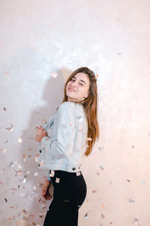 Pretty woman with smile posing on camera, standing on background of light wall.の写真素材