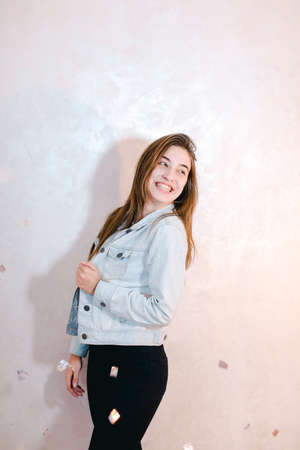 Pretty woman with smile posing on camera, standing on background of light wall.の写真素材