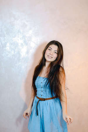Pretty woman with smile posing on camera, standing on background of light wall.の写真素材
