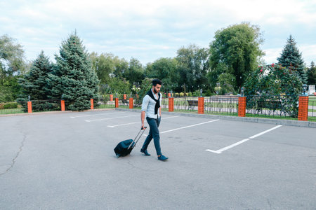 One Young Handsome Guy Arab Businessman Entrepreneur Tourist Traveler Visitor go With Suitcase For Trip in His Hand in Parking .の写真素材
