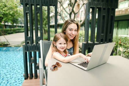 portrait of mother and daughter use laptop on background of swimの写真素材