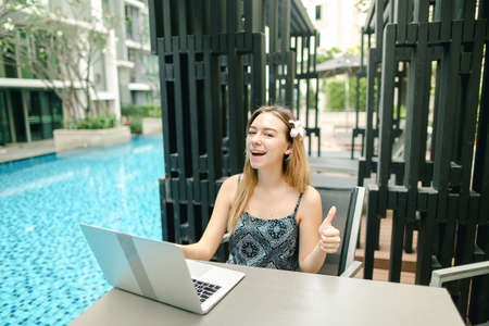 Portrait of girl with laptop by pool on sunny dayの写真素材