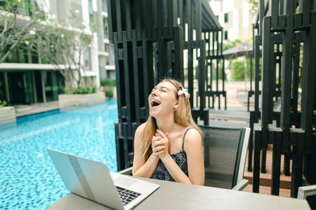 Young beautiful girl is very happy With laptop near pool on sunnの写真素材