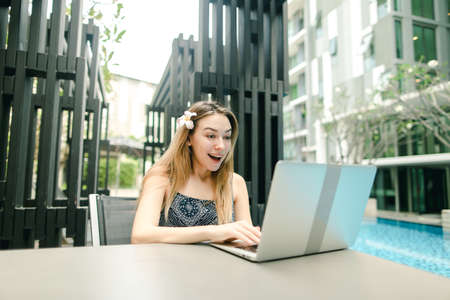 very joyful portrait of young girl with laptop sunny day by poolの写真素材