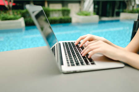 close up woman fingers pressing keyboard on laptop sunny day swiの写真素材
