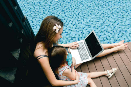 Close-up of female mother, daughter and laptop on background ofの写真素材